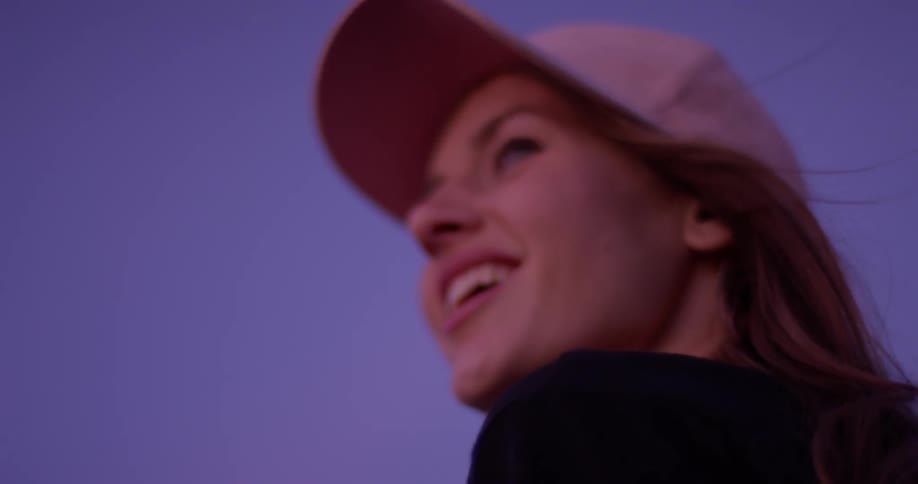 A woman standing on a rooftop at dawn is smiling as she looks at a city
