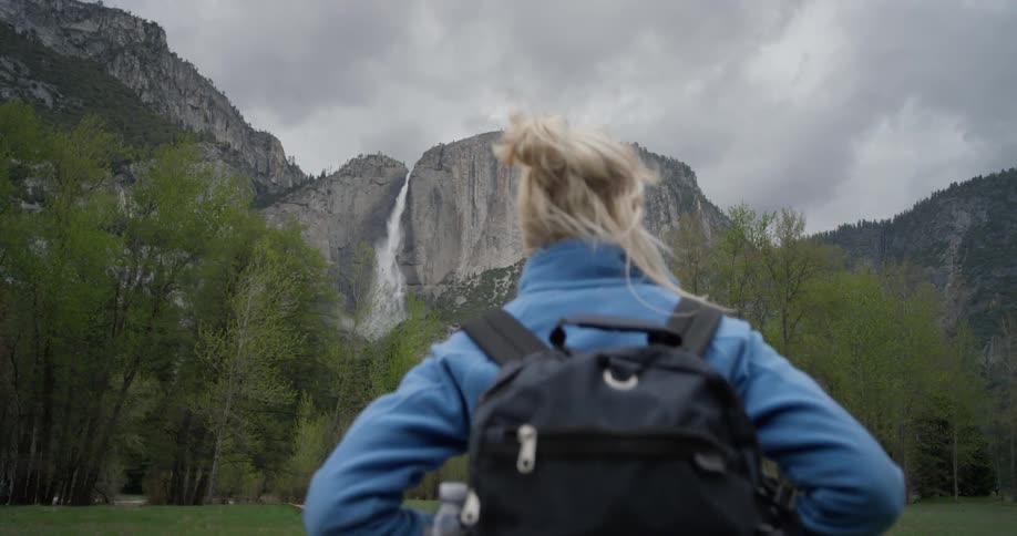A woman walks towards the mountain on a windy day