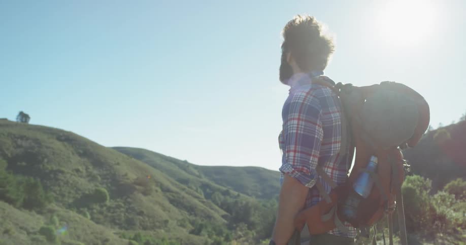 Man stands outside in the hills on a sunny day
