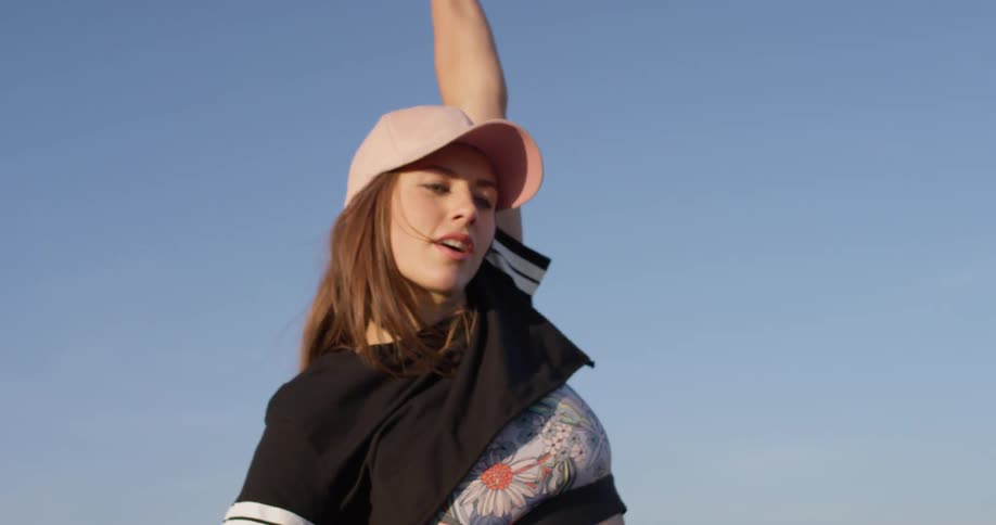 A woman in a pink hat dances outside