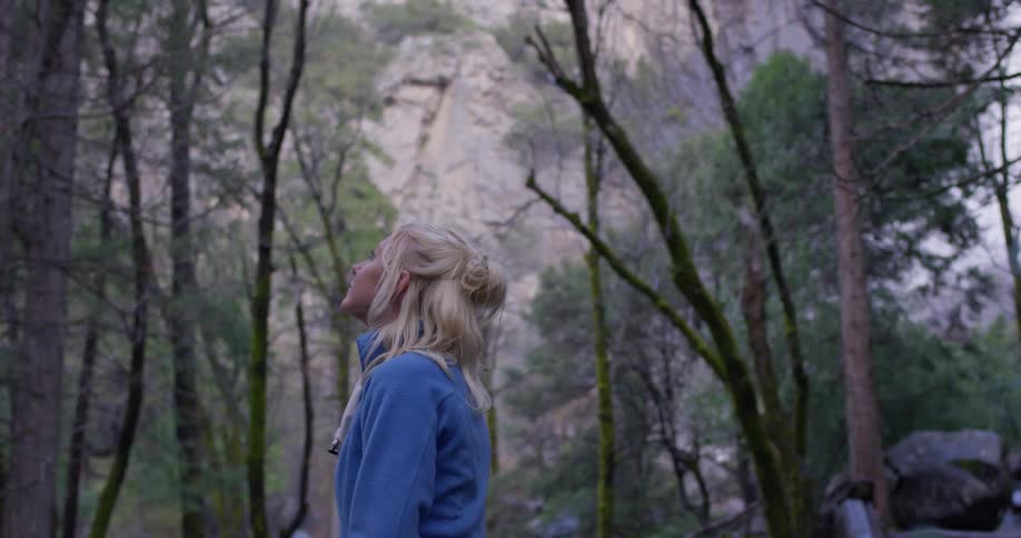 The woman is looking around the foggy forest