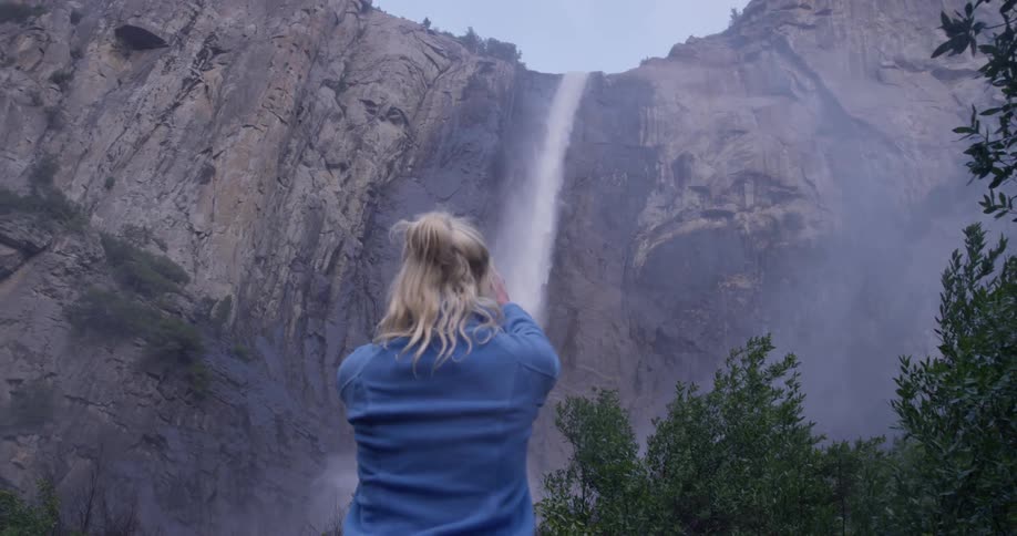 A woman walks over to photograph the waterfall