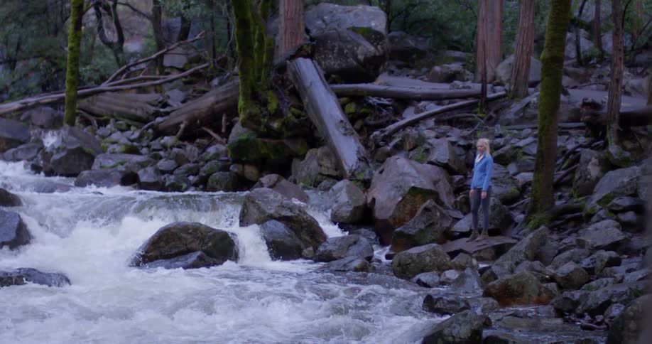 A woman watches the rough waters of the stream
