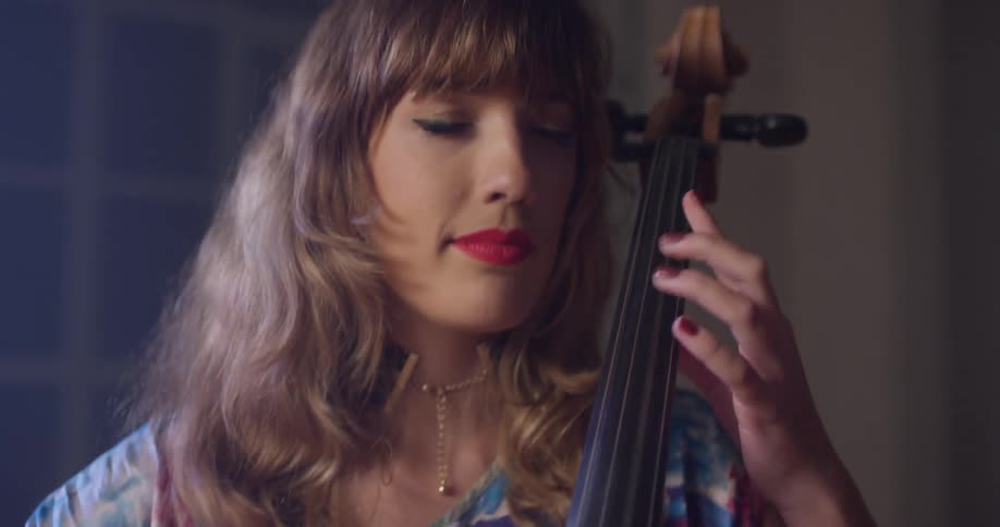 A woman smiles while playing a cello