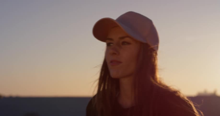 A woman in a pink hat dances on a rooftop