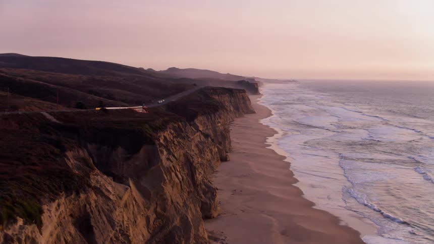 Ocean waves flow towards a shoreline at sunset