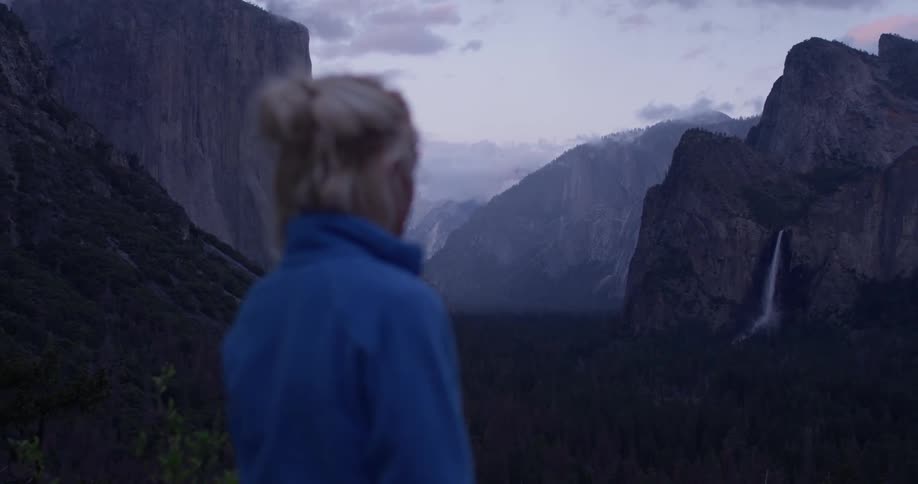 A woman hikes in mountains at sunset