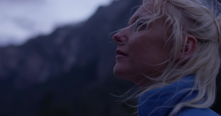 A woman looks around the mountains on a windy day