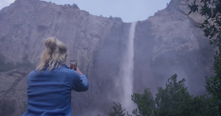 Woman takes a picture of a large waterfall