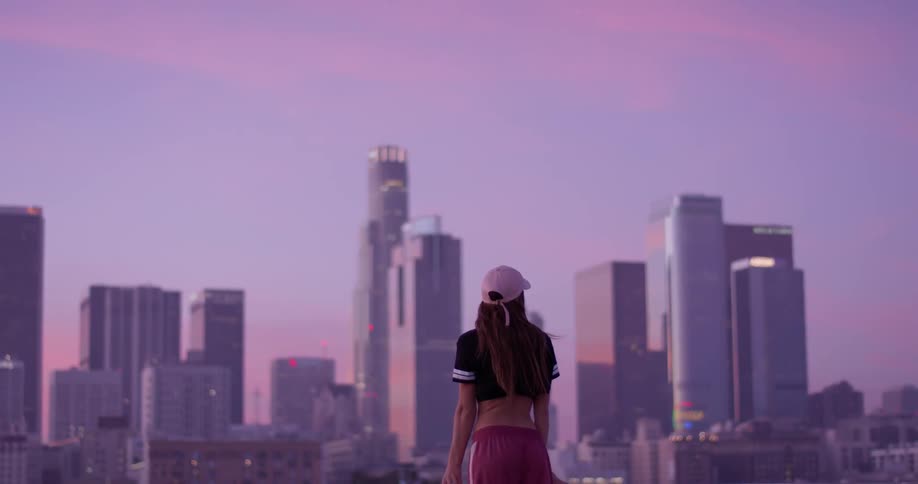 A woman in a pink hat stands atop a rooftop