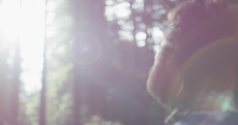 A man with a beard looks around in the woods