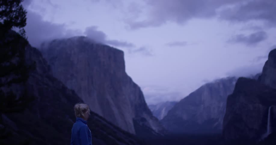 A woman is taking in a view of a yosemite valley on a cloudy morning