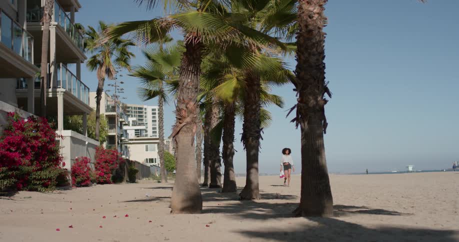 A woman carries roller skates on the beach