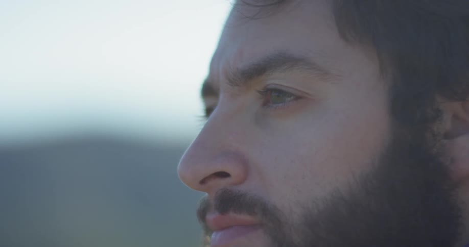 A man in a beard looks around outside