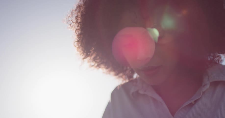 The sun shines behind a woman outside