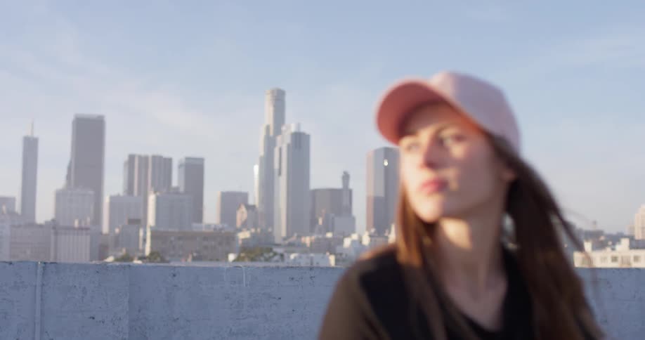 Woman stands on a rooftop in the city looking down