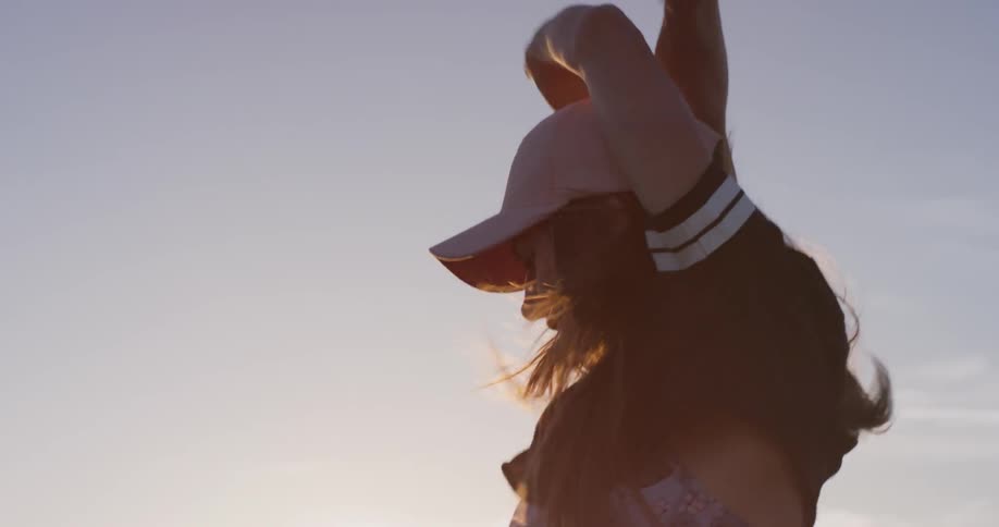 A woman in a pink hat dances outside