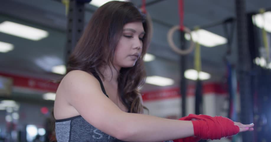 A woman tapes up her hands in the gym