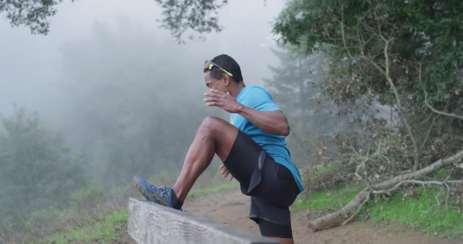 A man stretches in a foggy forest