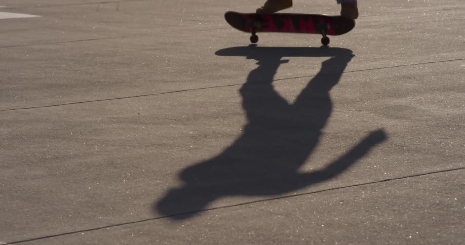 The shadow of a person flipping their skateboard