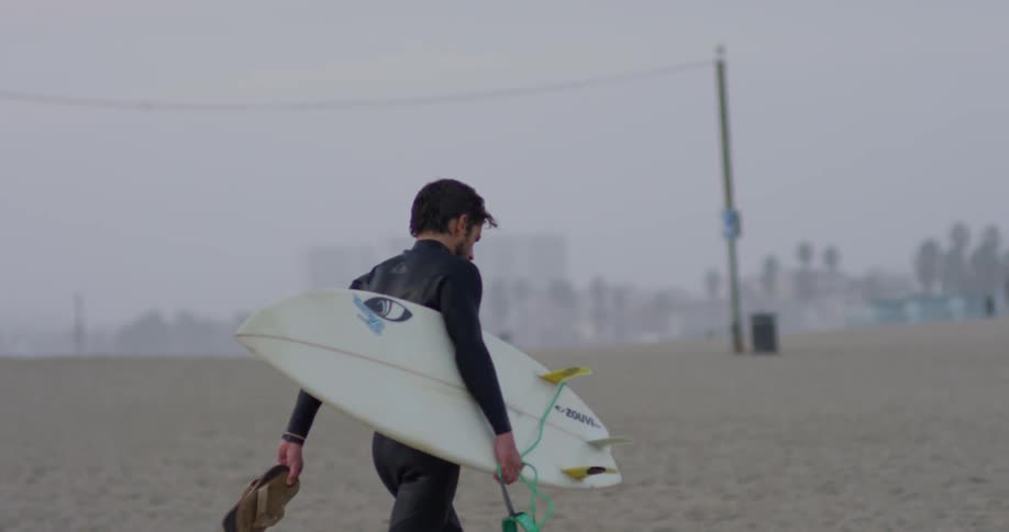 A man carries a surfboard on a beach