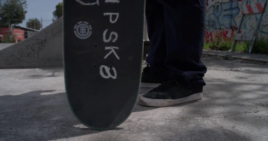 A skateboarder twirls his skateboard