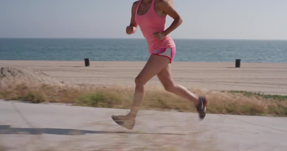 A woman jogs on a path by the beach