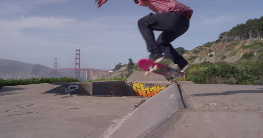 A skateboarder is riding down a ramp outside near the golden gate bridge in daylight