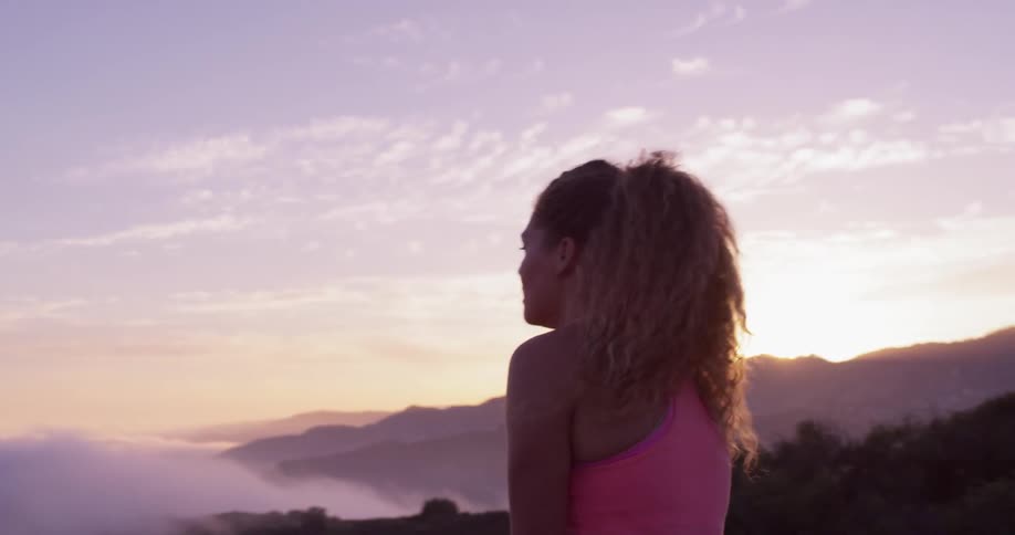 Woman walks in nature and looks out over foggy hills