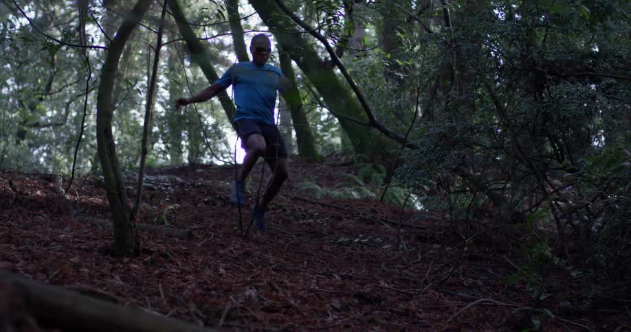 A man runs and leaps down a slope in the woods