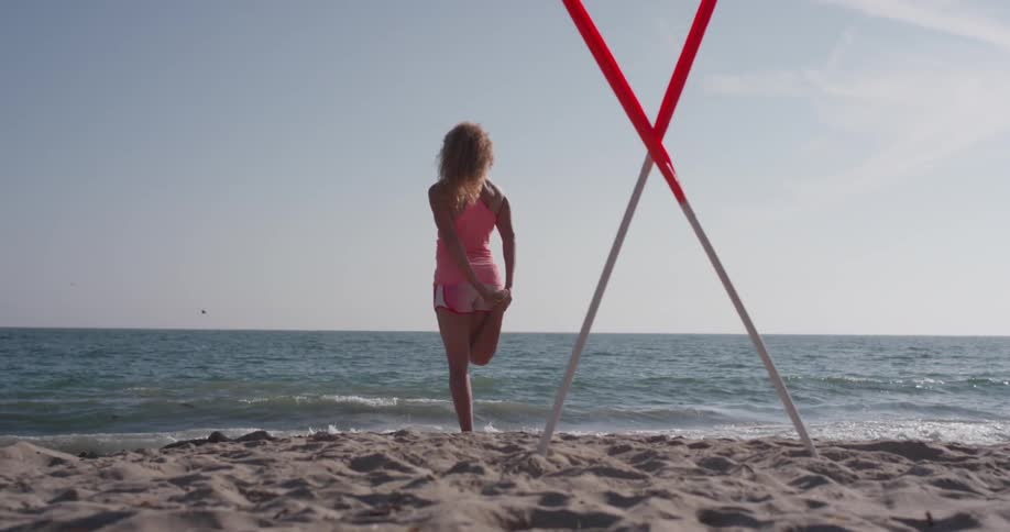 A woman stretches on a sandy beach