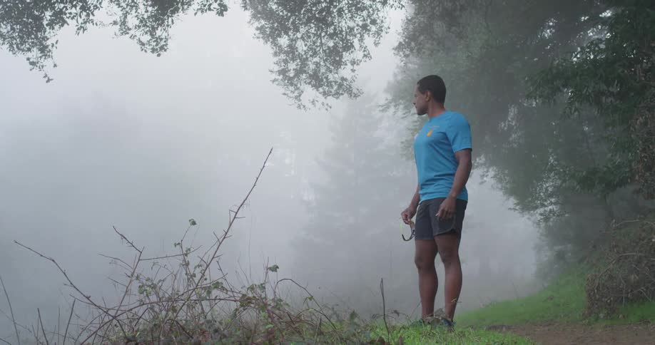 A man looks out into the haze from the hill