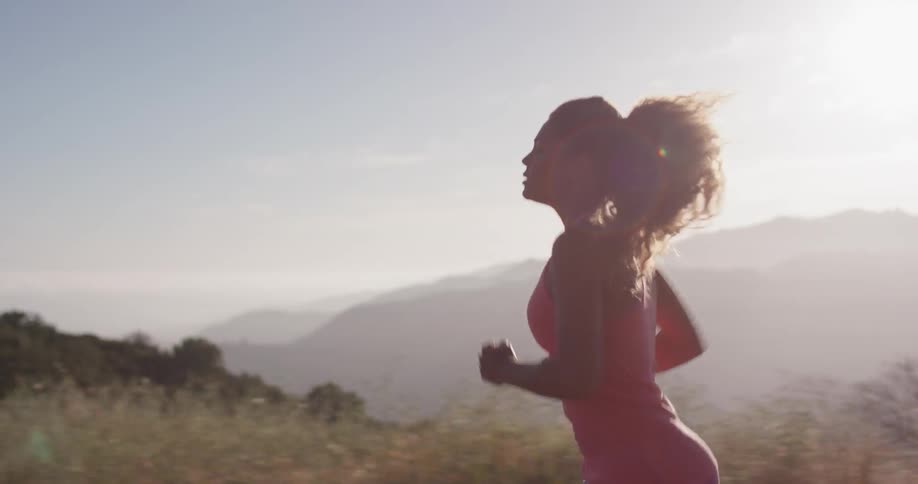 Woman is jogging near mountains at sunset
