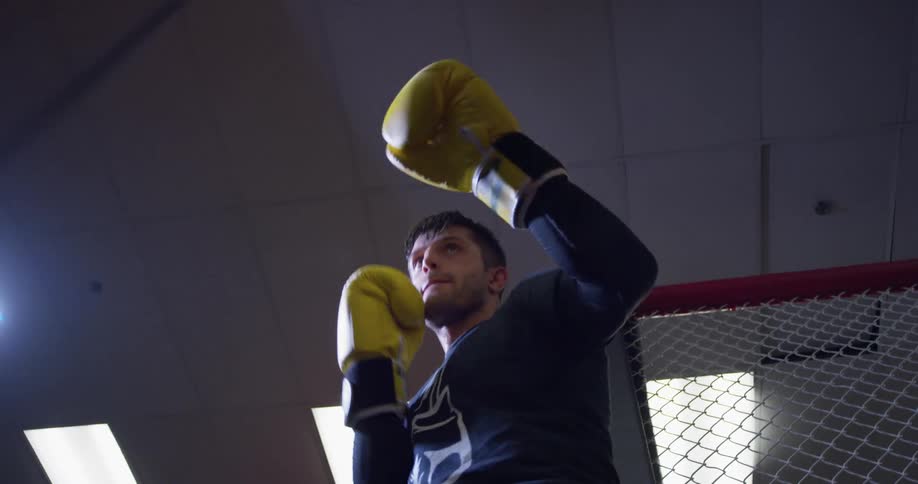 Man wearing boxing gloves punches a punching bag