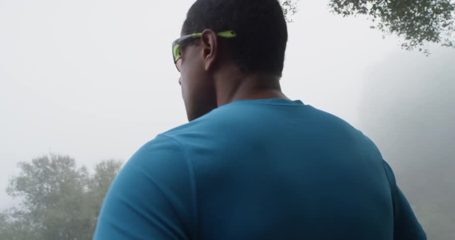 Man wearing sunglasses looks out into the foggy woods