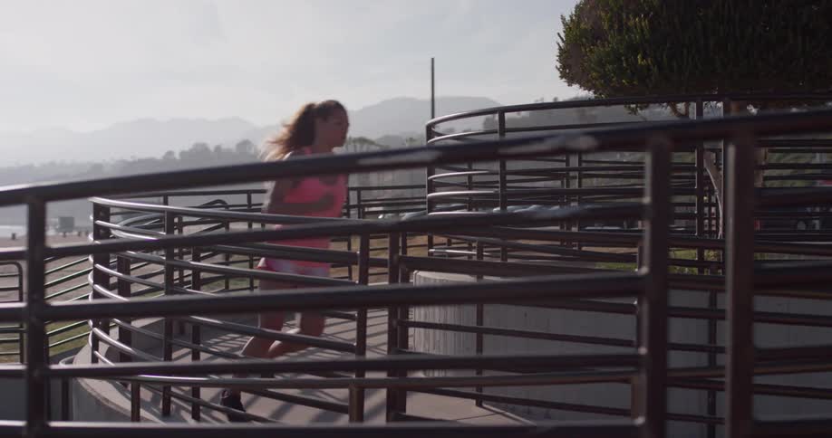 The woman is running around the stairs near the beach