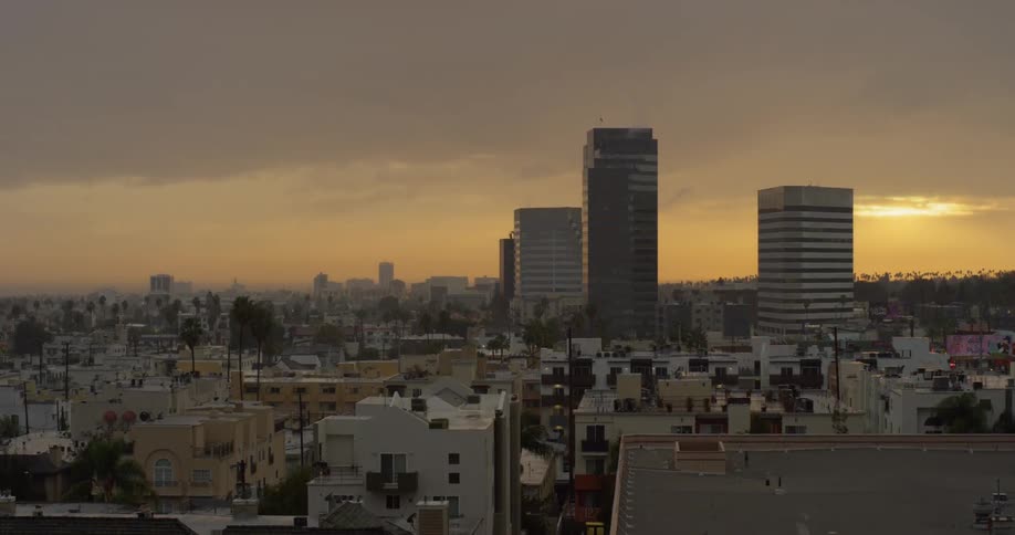 The sun sets behind city buildings