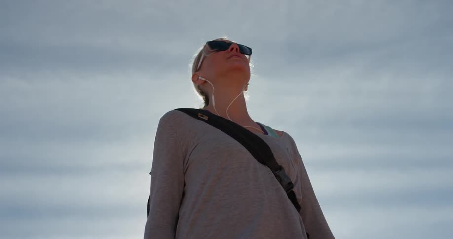 A blond haired woman stands outside in the sun