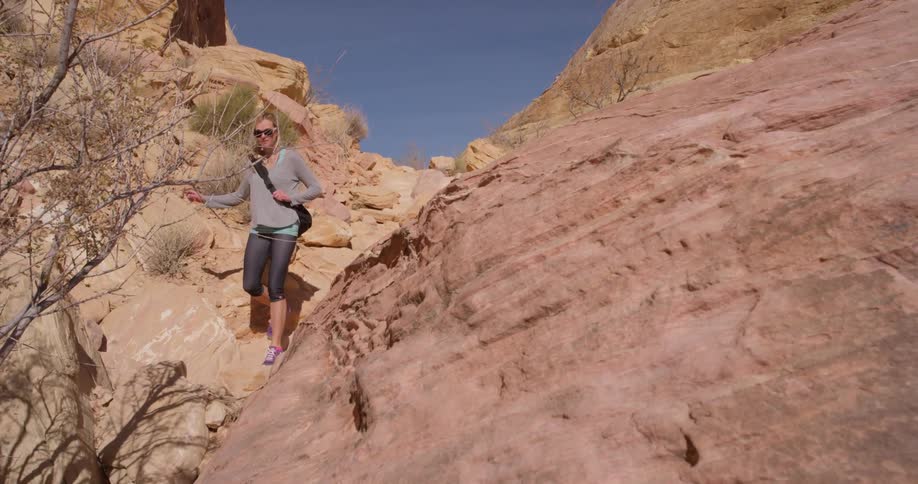 A woman treks down a rocky slope