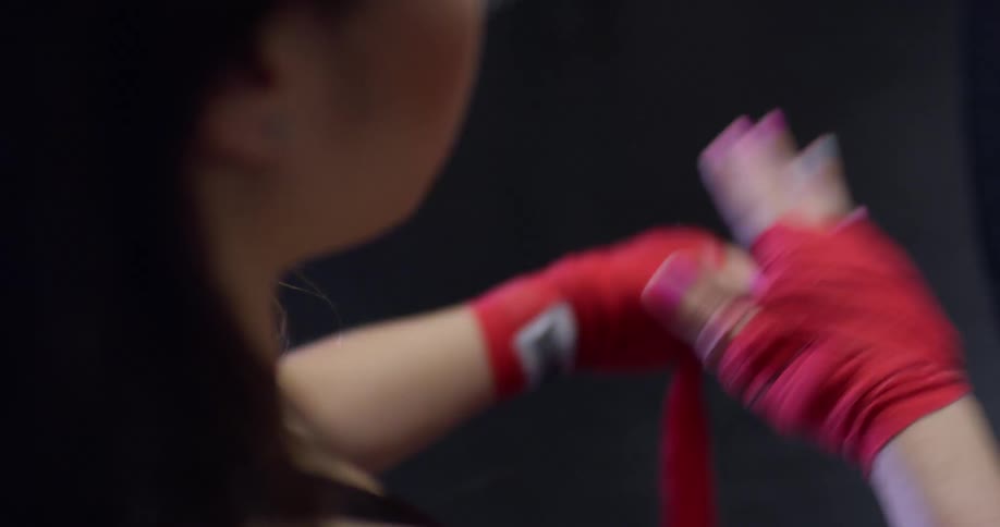 A woman unwraps her wrists inside a gym