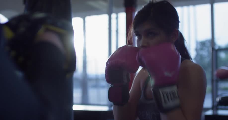 Woman in gym punches heavy bag