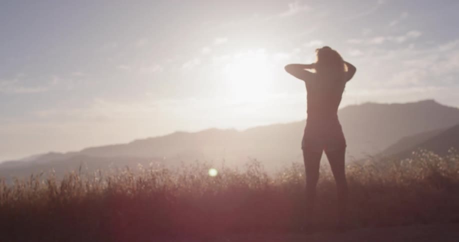 A woman stands outside under the sun