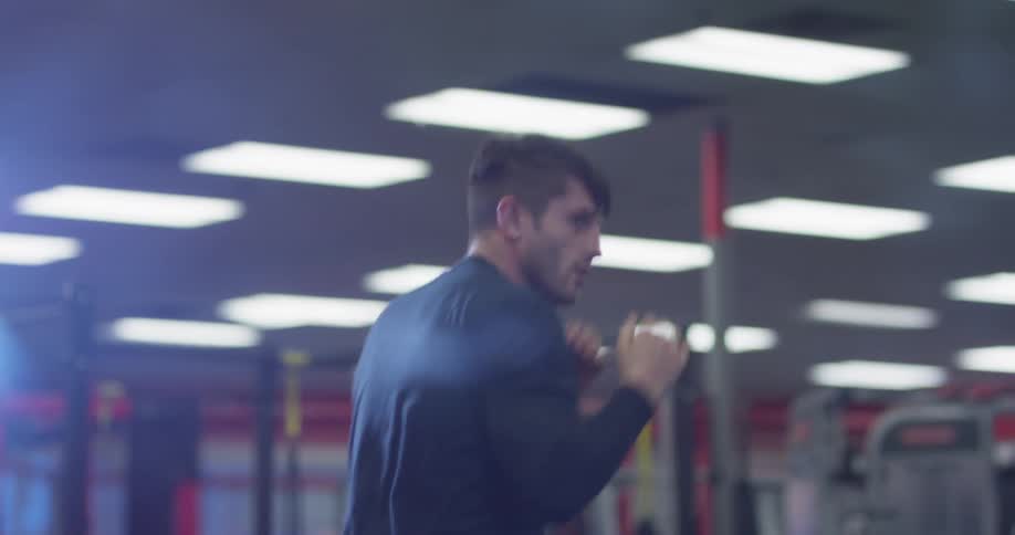 A boxer punches the air in a gym