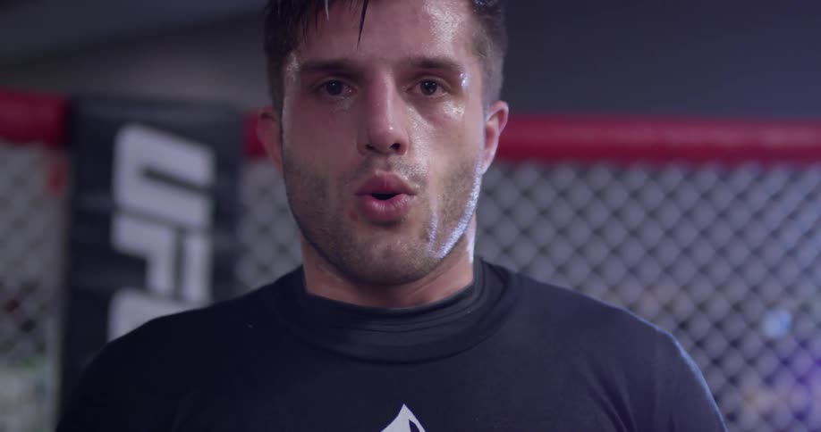 A boxer is sweating and breathing heavy as he stands inside in daylight