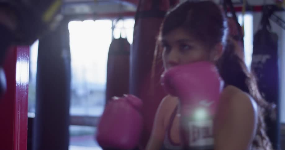 A female boxer spars in a gym