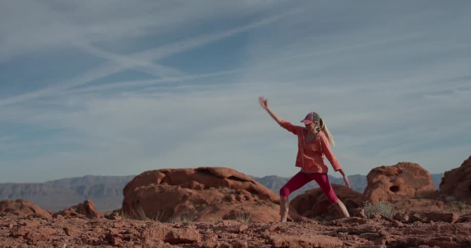 Woman stretches while standing on rocky terrain