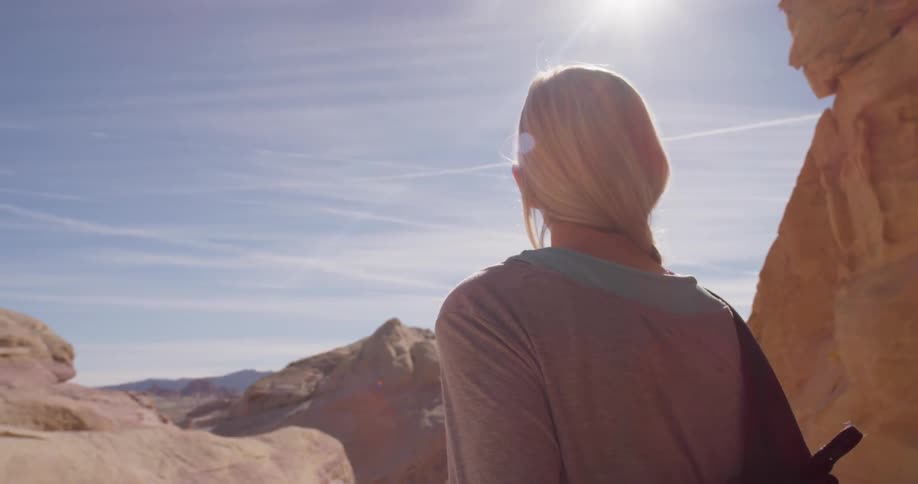 Woman is standing and observing rocky wilderness on sunny day