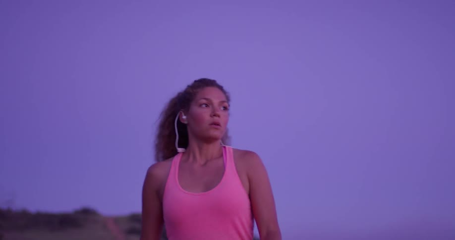 Woman walks outside and puts earbuds in her ears