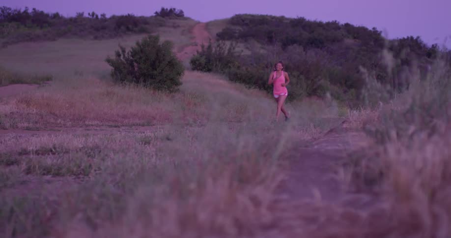 A woman jogs in a rural area at sunset