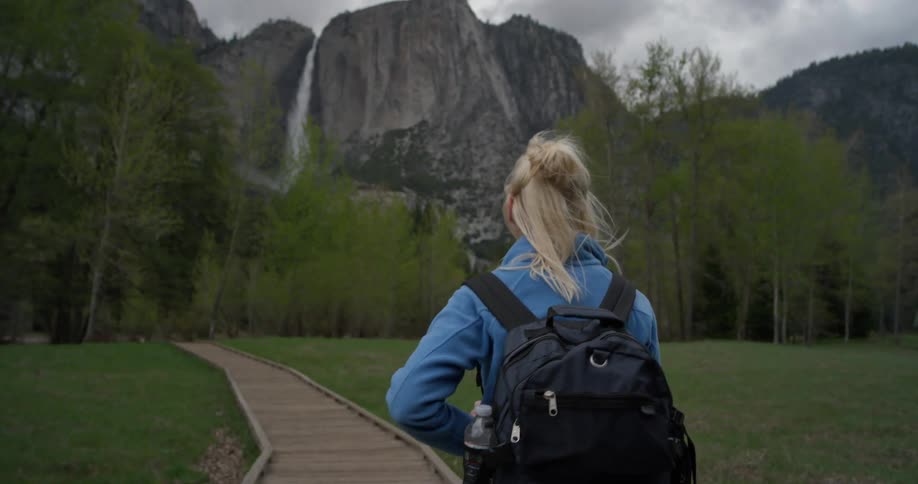 A woman is hiking on a trail towards the mountain